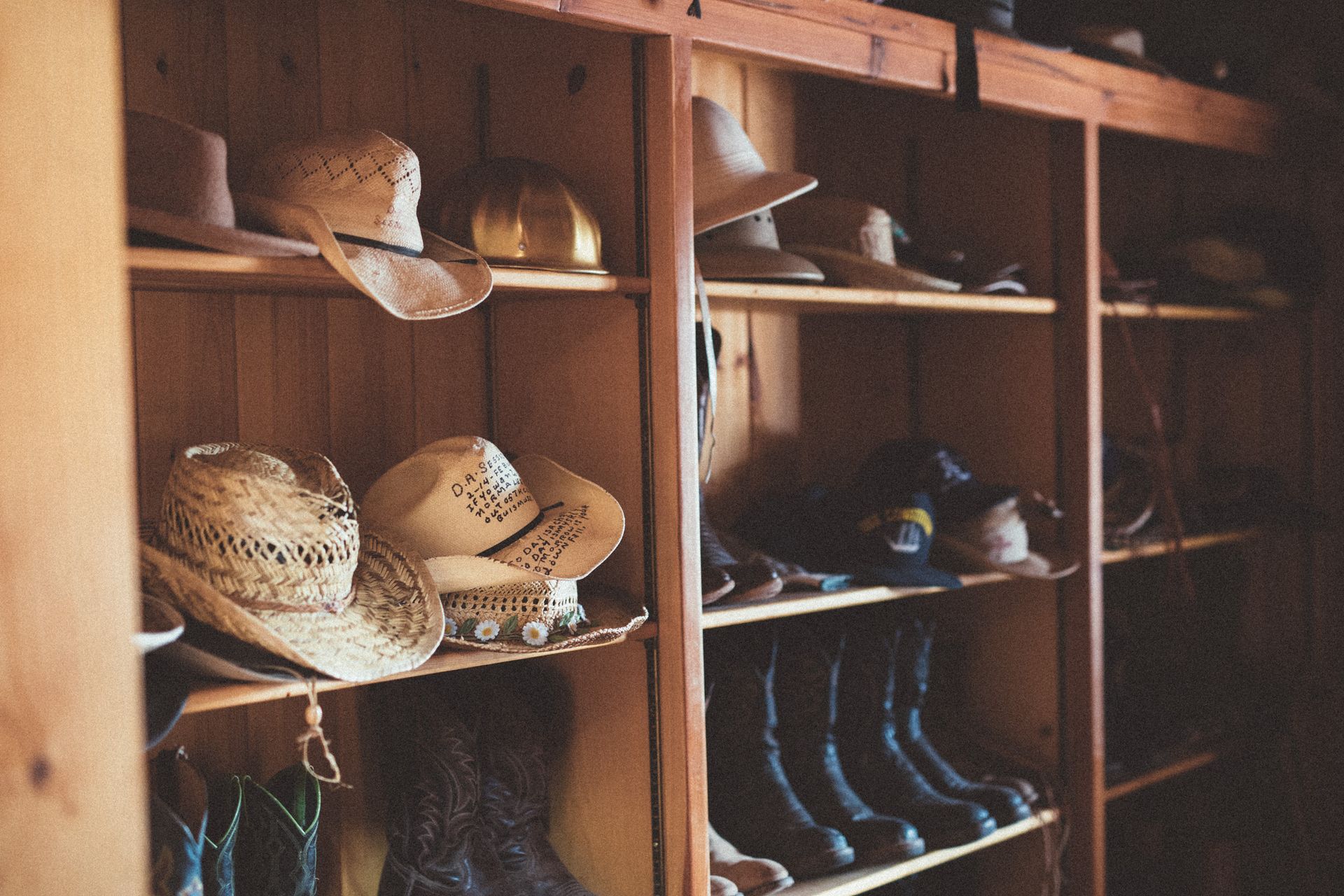 Wooden shelves filled with assorted hats and shoes in a rustic closet