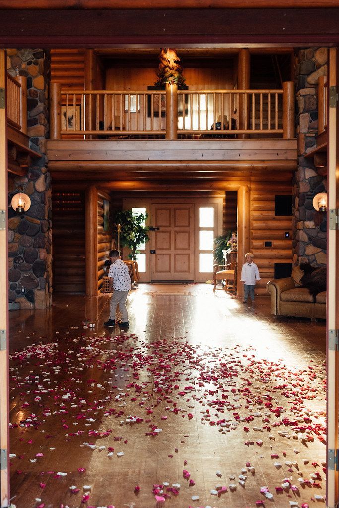 Wooden lodge foyer with a flower petal-strewn floor and balcony above the entrance