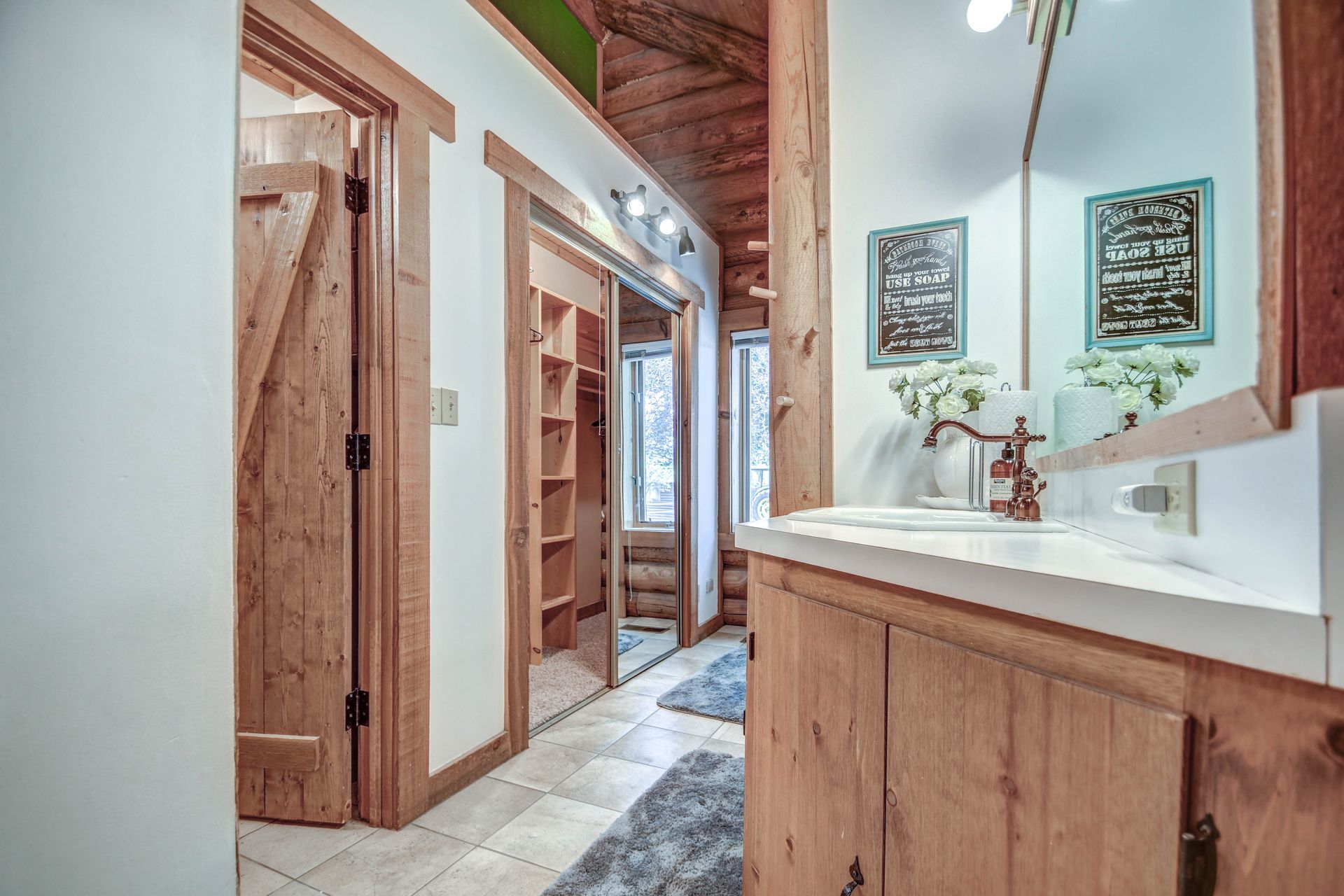 Rustic bathroom with wood vanity, stone sink, and hallway view to a walk-in closet