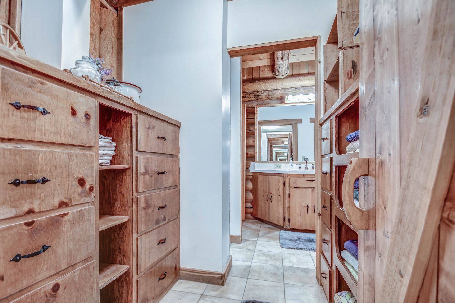 Rustic wood-paneled hallway with built-in drawers and shelves leading to a bathroom.