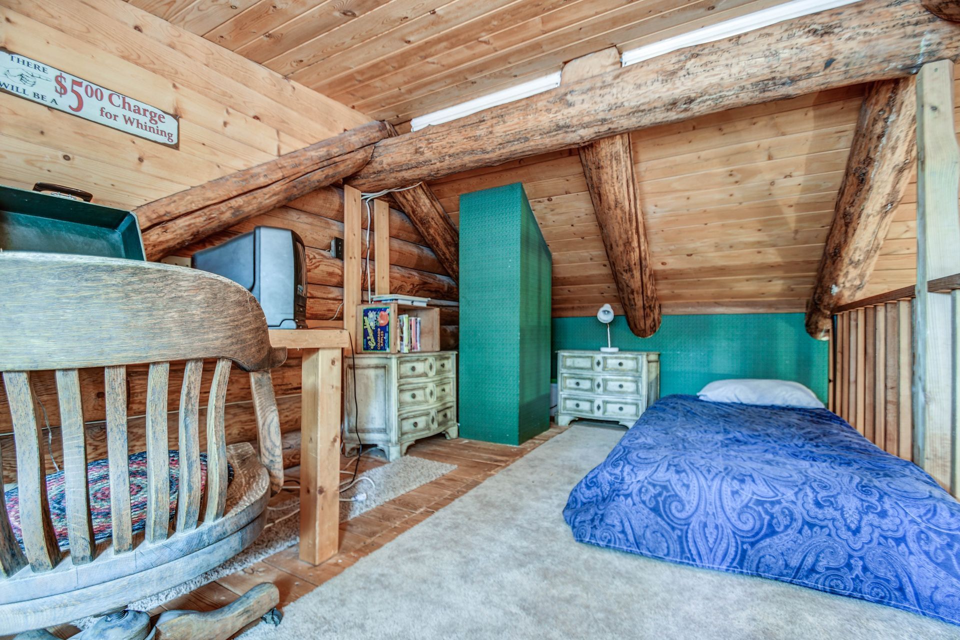 Wooden loft bedroom with a blue bed, storage cabinets, and exposed beams