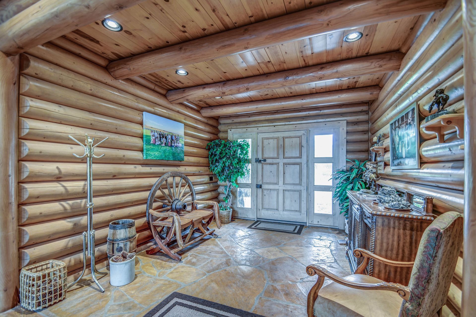 Rustic log cabin entryway with wagon wheel decor, wood furniture, and bright front doors