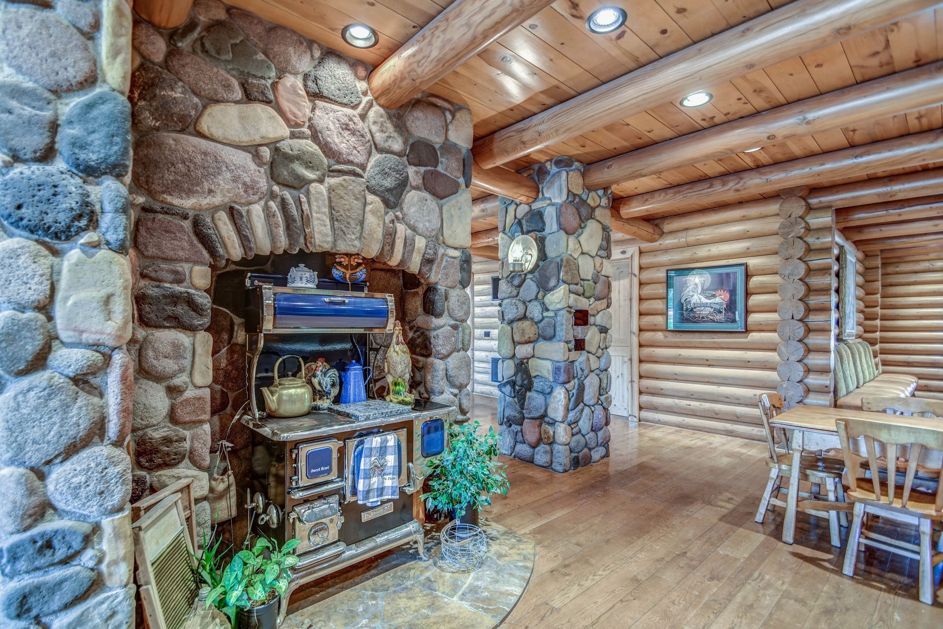 Rustic log cabin interior with stone fireplace, wooden furniture, and warm overhead lighting