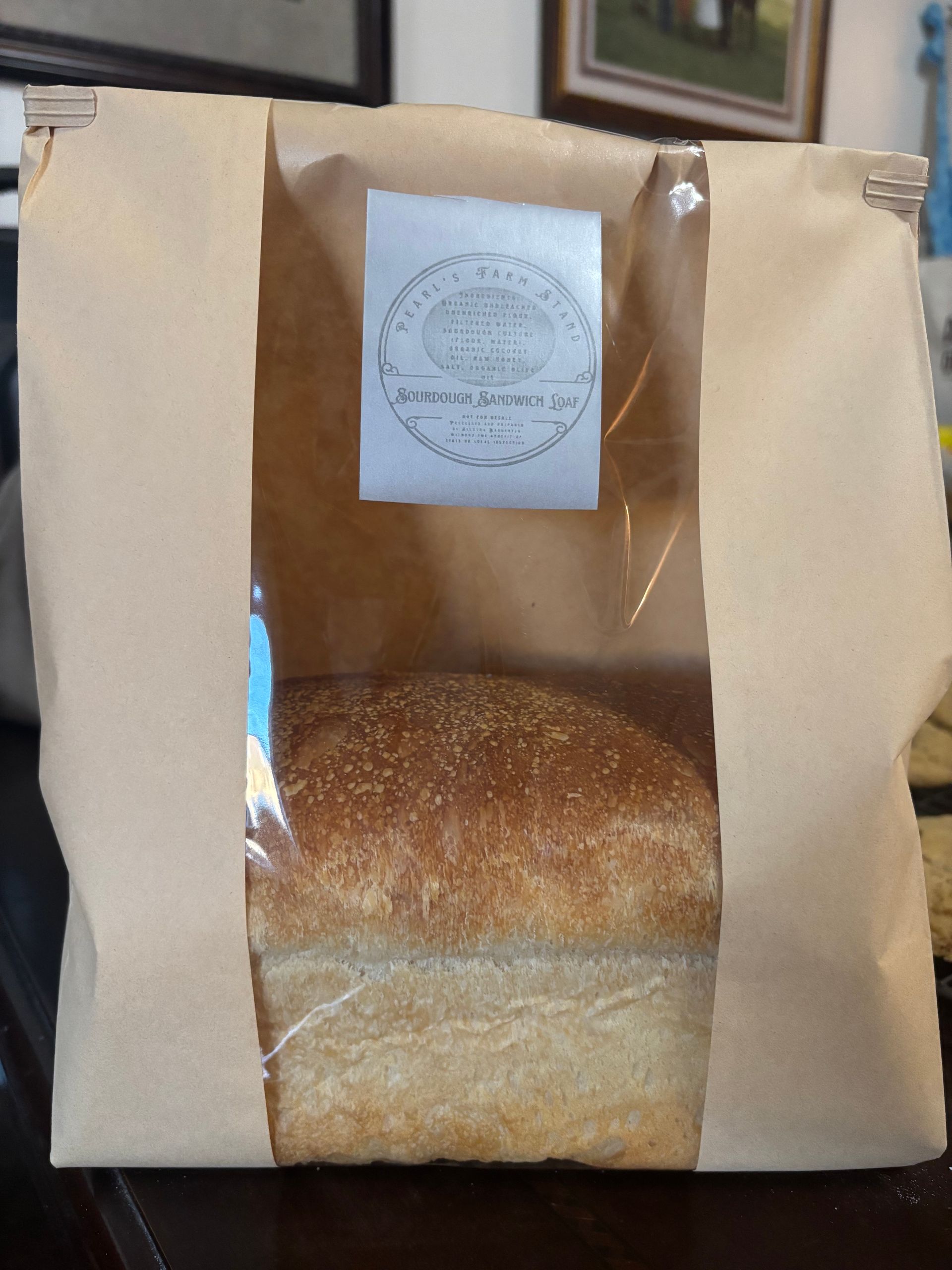 Brown paper bakery bag with a window showing a loaf of bread inside