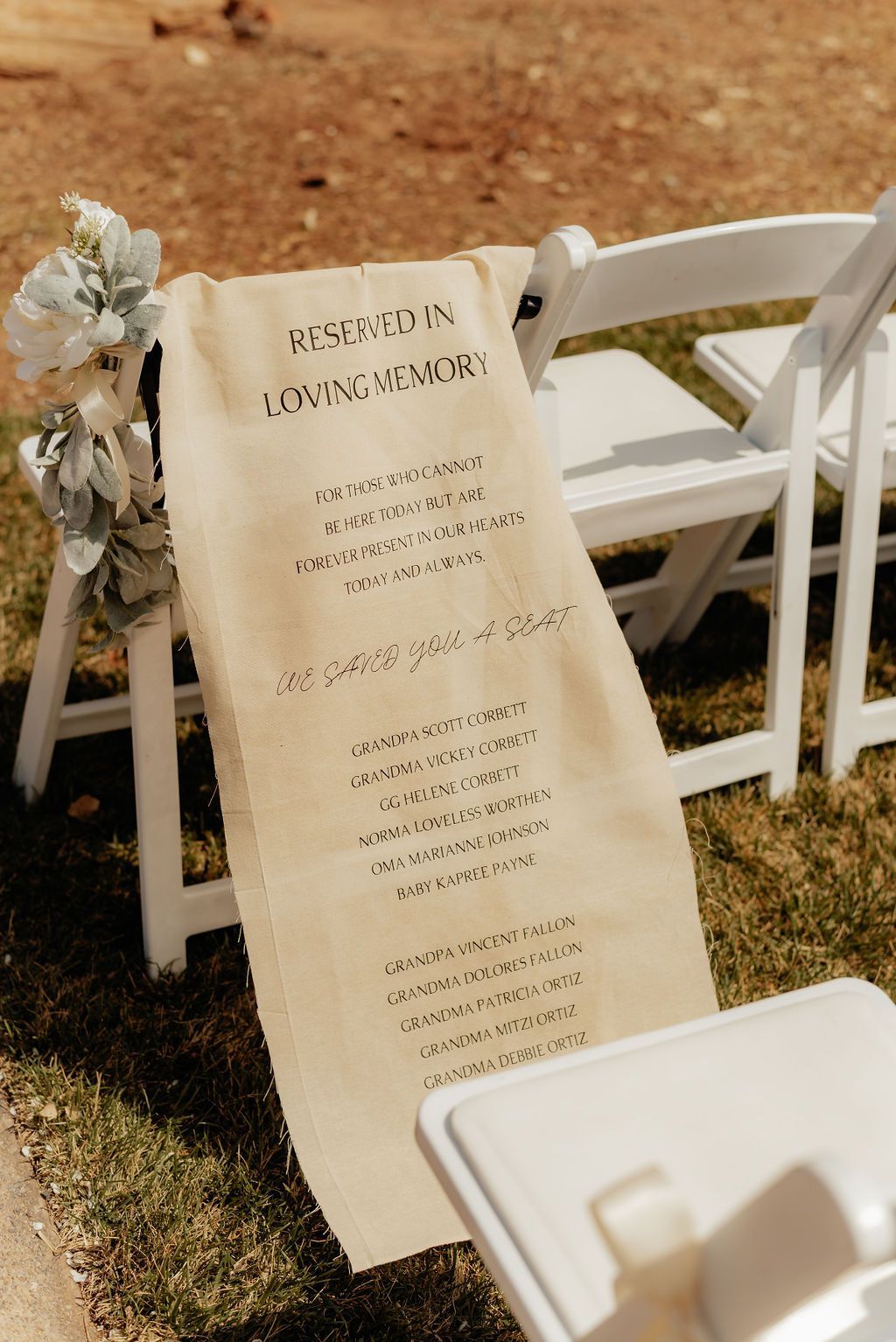 Wedding ceremony program draped over a white chair outdoors on grass