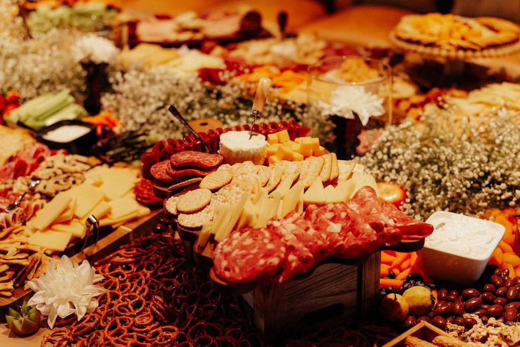 Charcuterie board with assorted cheeses, cured meats, crackers, and flowers on a rustic table