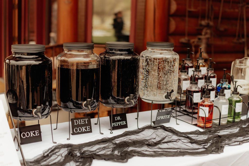 Assorted Coke dispensers and glass bottles arranged on a white tablecloth in a banquet setting