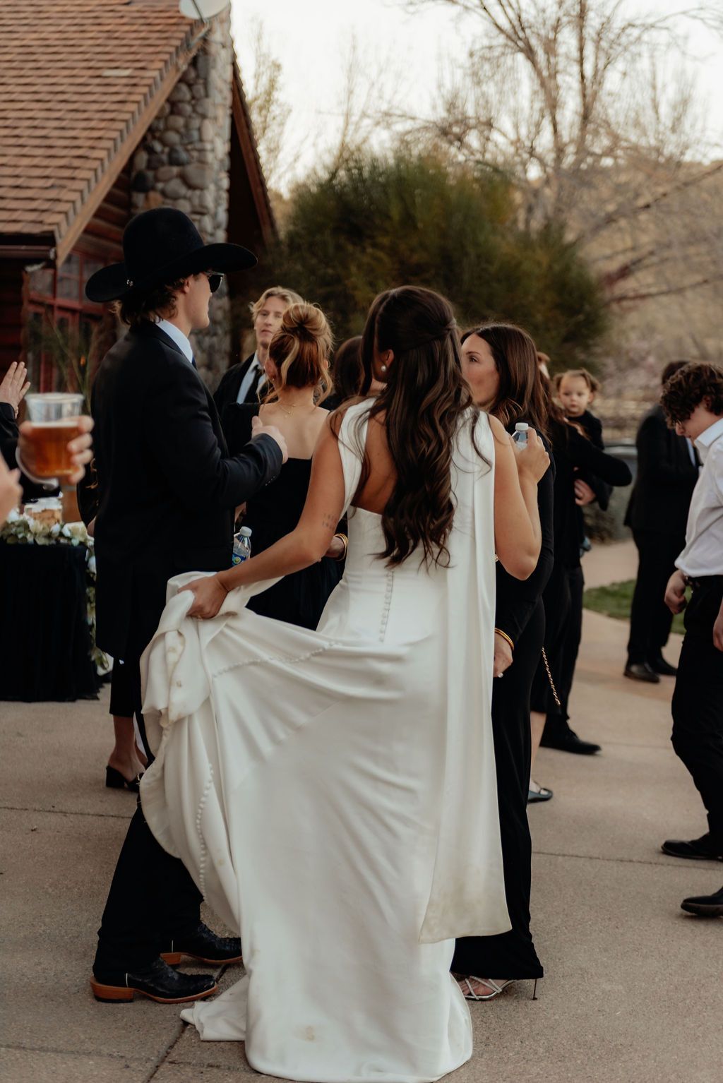 People dancing at an outdoor formal event, with a woman in a white dress in the foreground