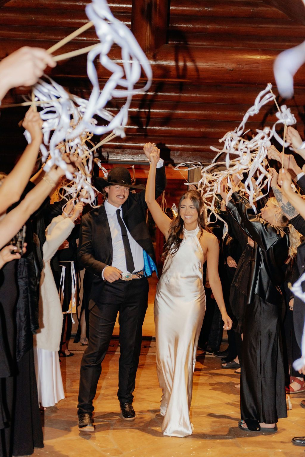Couple in formalwear walking through confetti streamers at a celebration event