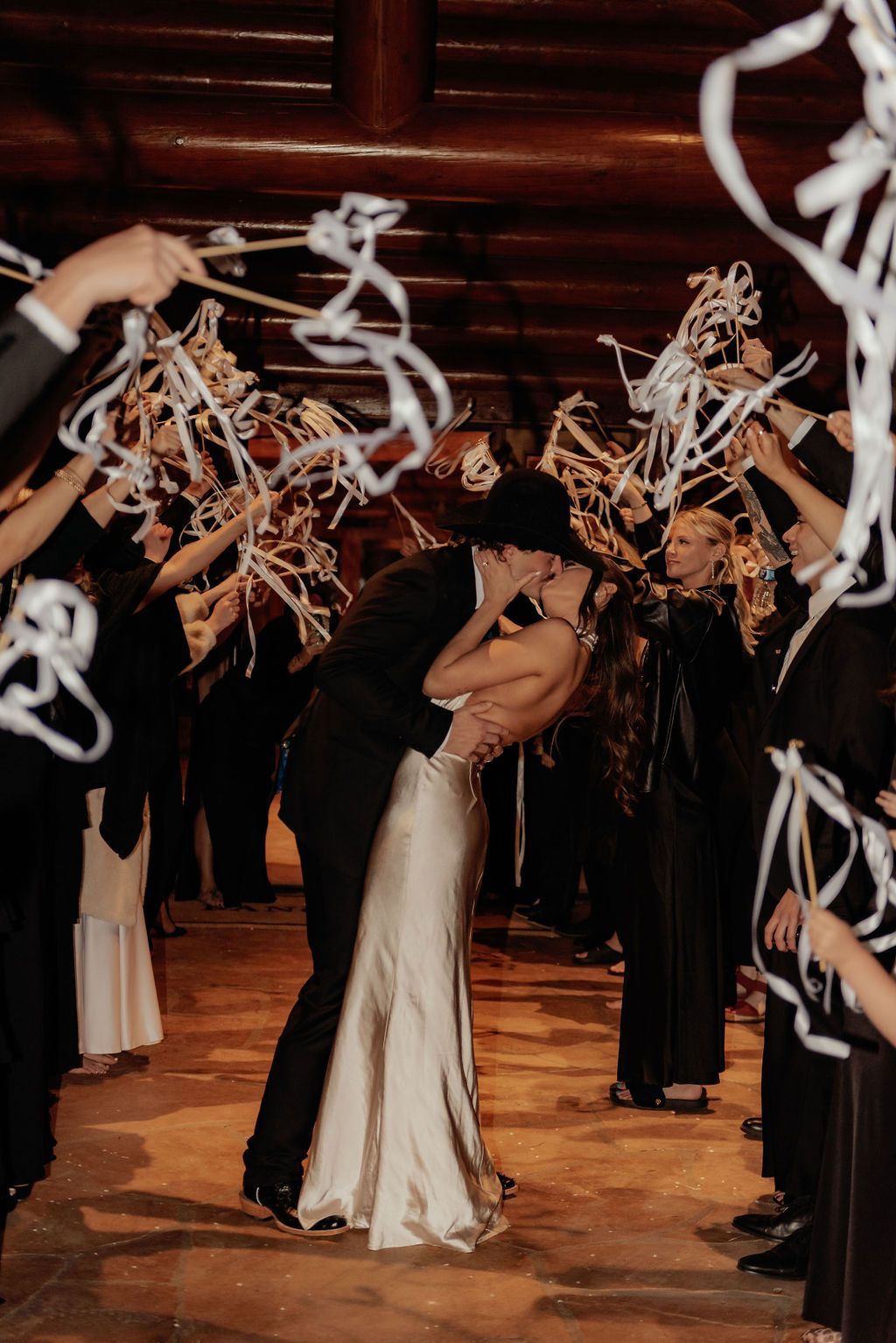 Person in a white dress dances through an arch of streamers at a festive indoor event