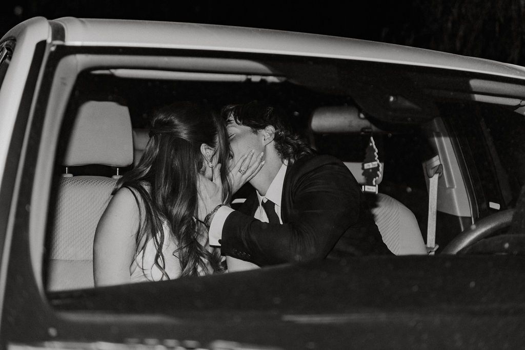 Two people kissing in the back seat of a car at night
