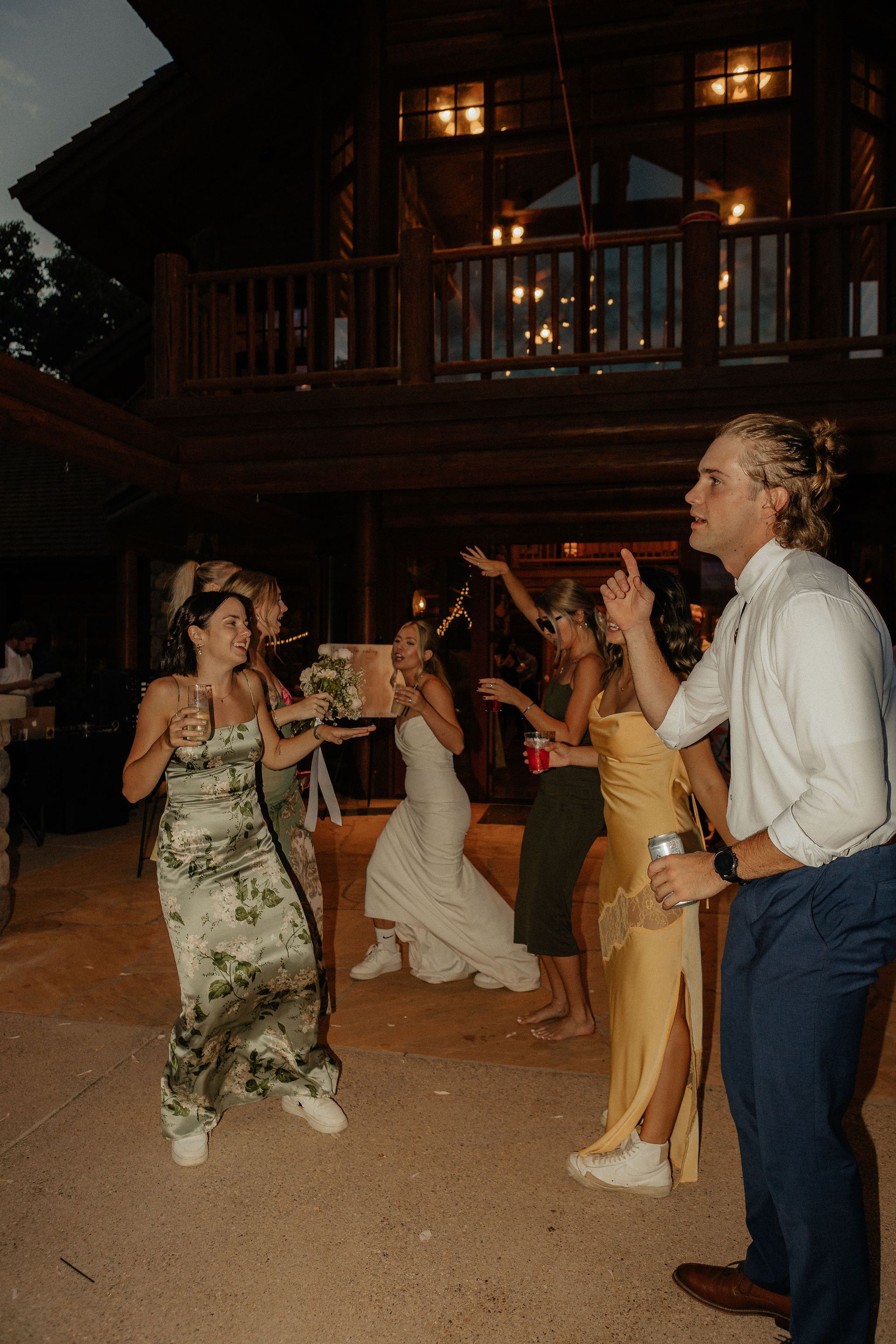 People dancing at a nighttime outdoor party in front of a lit wooden building