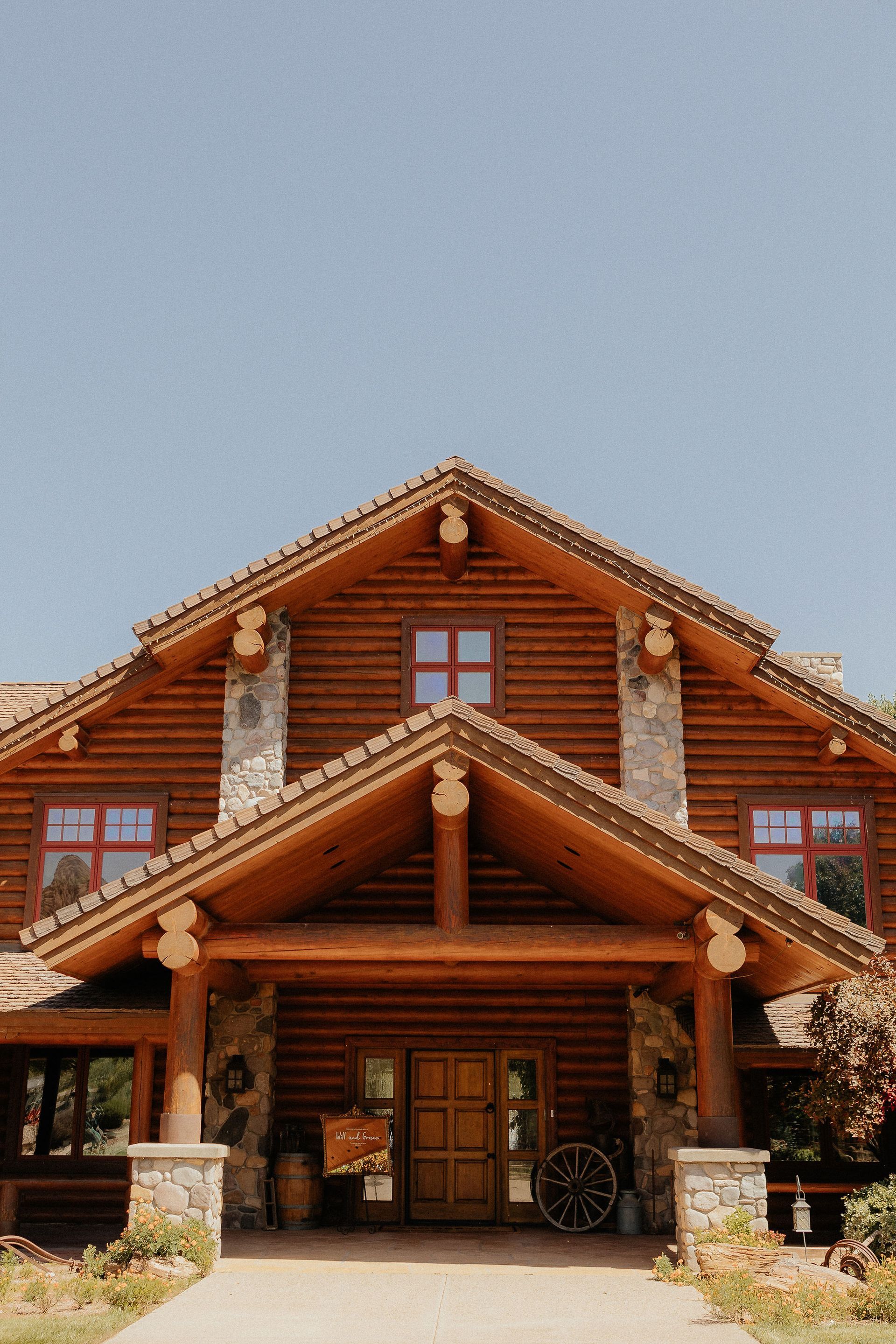 Rustic log cabin with a steep gabled roof and front porch under a clear sky