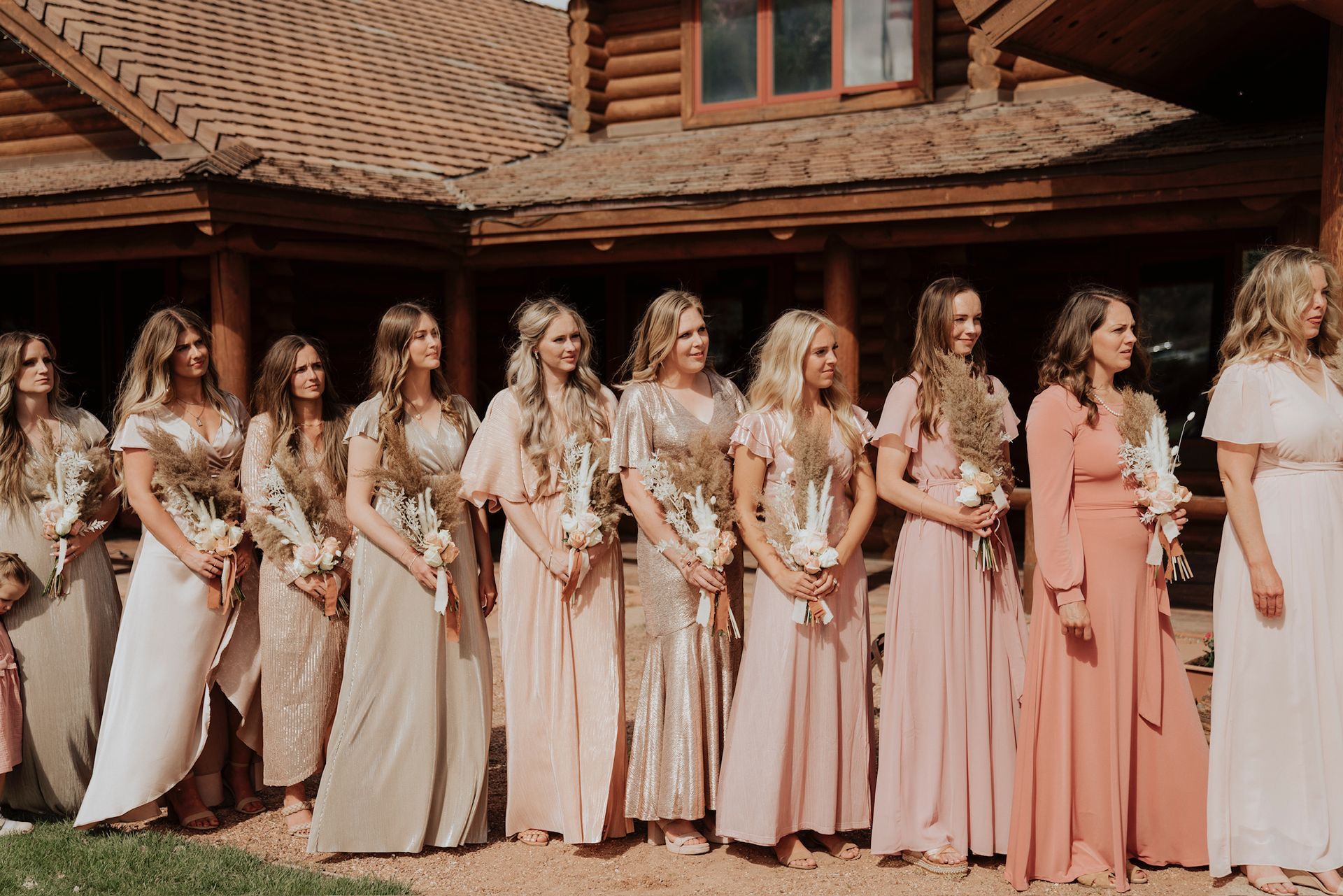 Group of women in pastel dresses standing outside a house with a red tile roof.