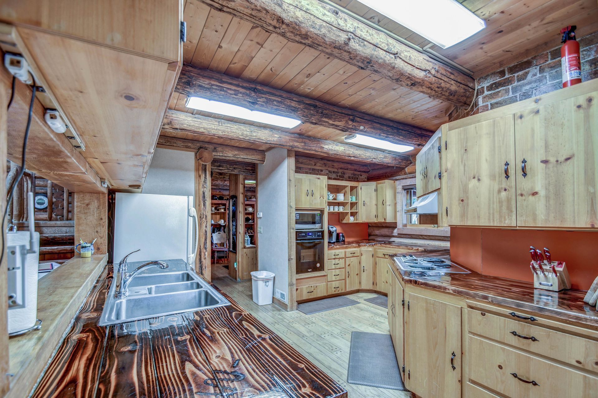 Rustic kitchen with wood cabinets, metal countertops, and bright fluorescent ceiling lights