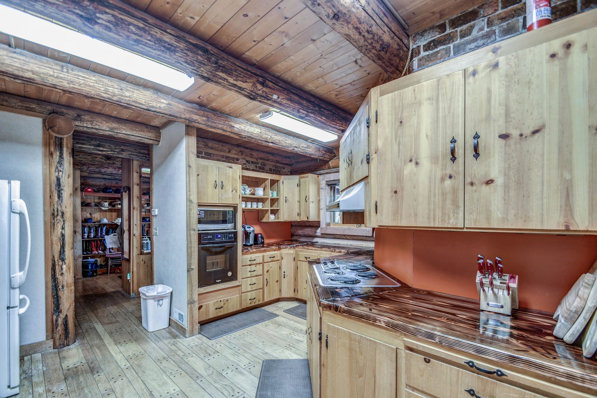 Rustic kitchen with wooden cabinets, granite counters, and vaulted wood ceiling