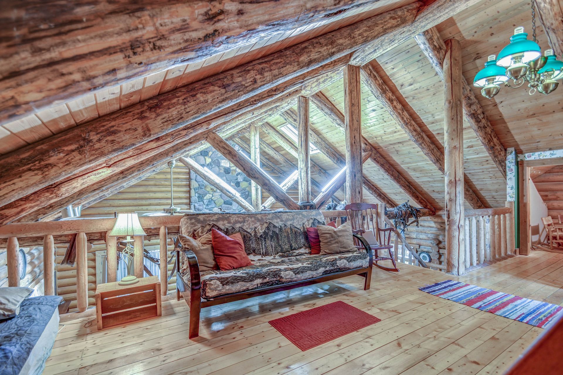 Loft living room with exposed wood beams, sofa, colorful rug, and skylight windows