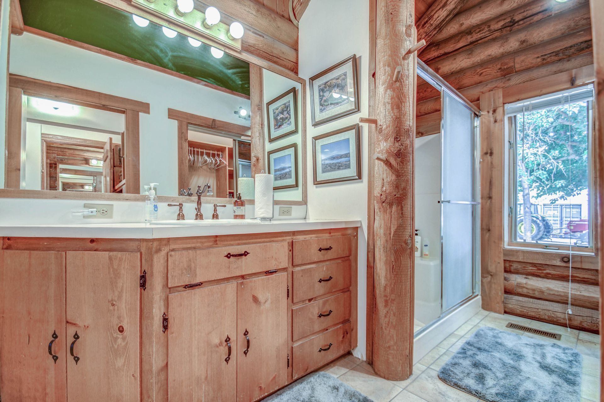 Rustic bathroom with wooden vanity, double sinks, mirrors, and a glass shower