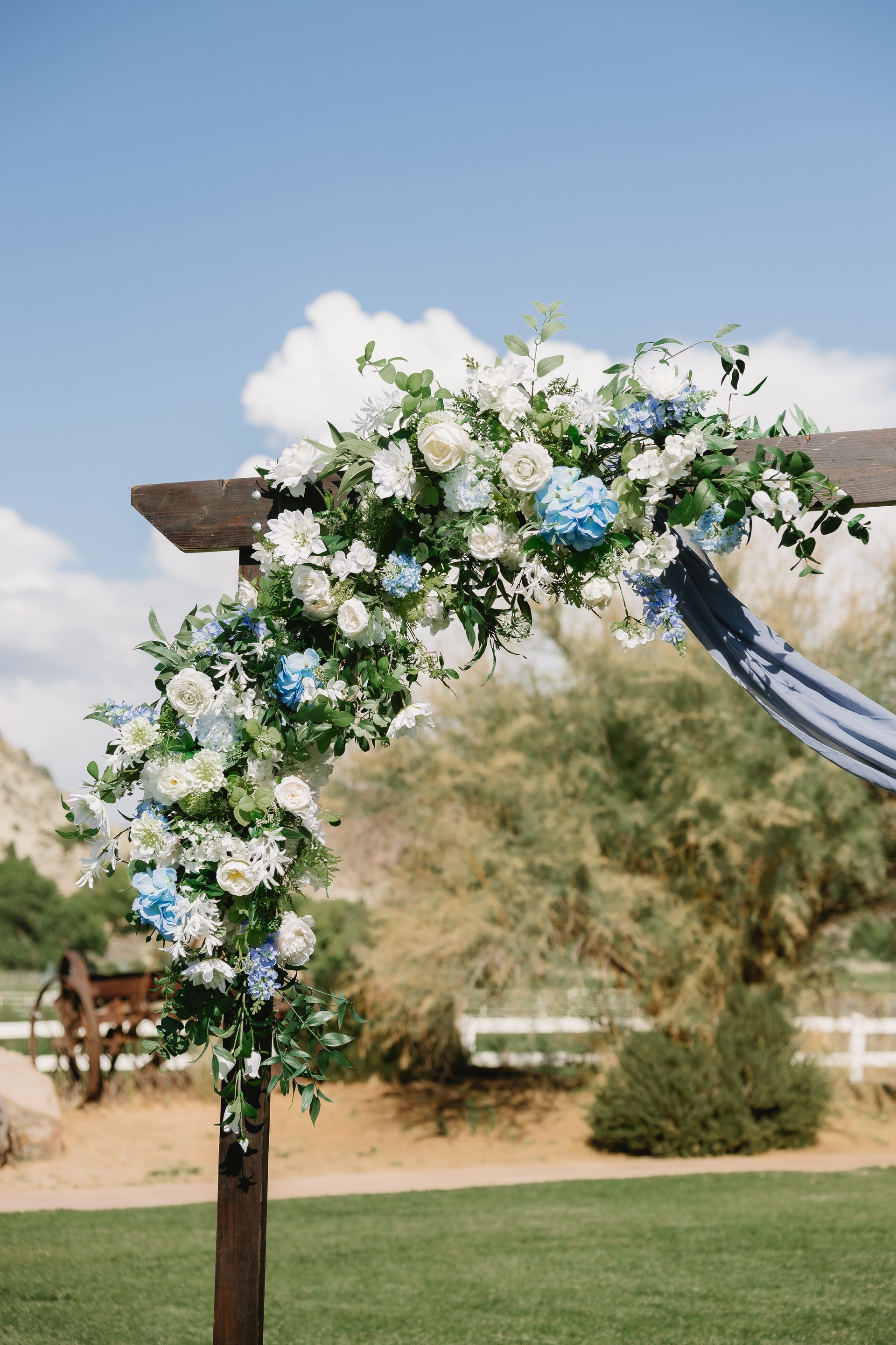 Floral wedding arch with white and blue flowers outdoors under a clear sky