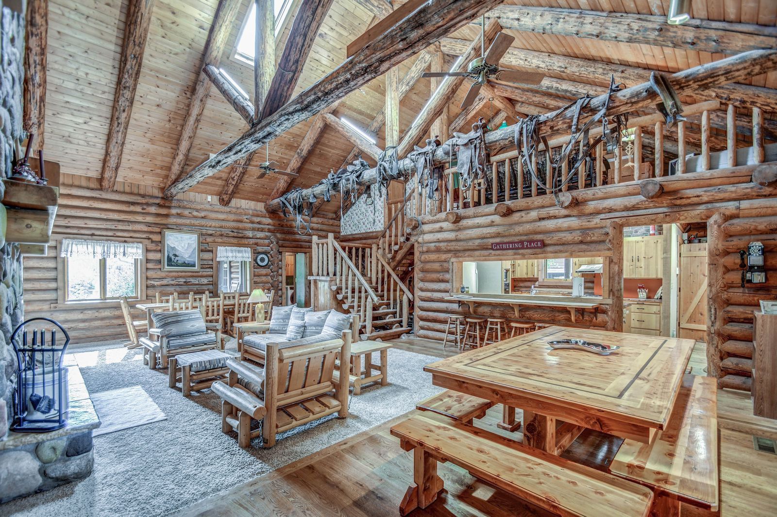 Rustic log cabin interior with wooden furniture, high beams, and sunlight from skylights