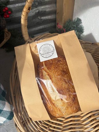 Brown paper bag holding a loaf of bread in a wicker basket with a white label on top