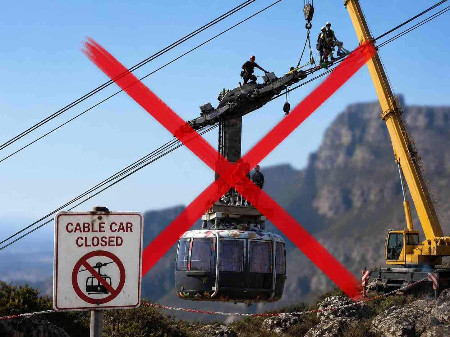 Cable car suspended above a mountain with a large red X and a “Cable car closed” sign