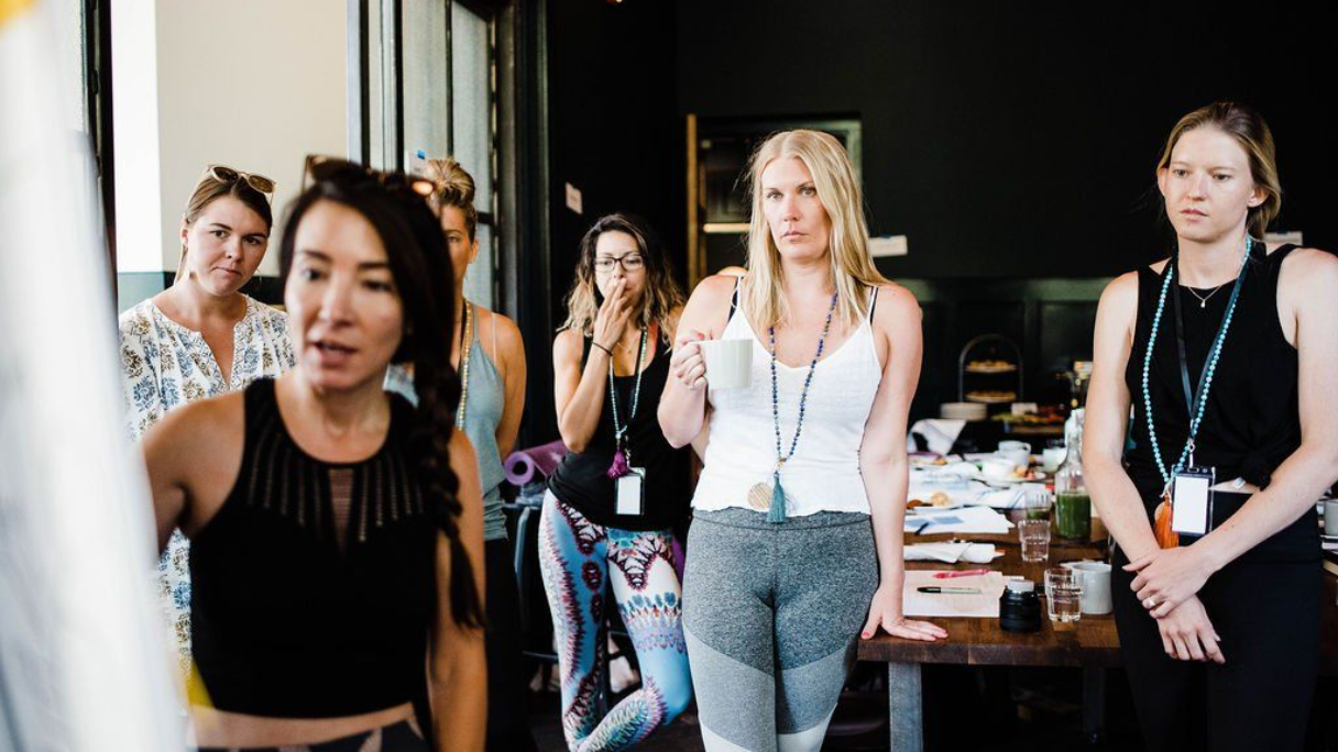A group of people in an office. One woman speaks, others look on with various expressions.