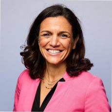 Woman in pink blazer smiles at camera.