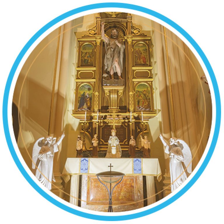 Ornate church altar with gold decorations, statues, and a crucifix under soft interior lighting