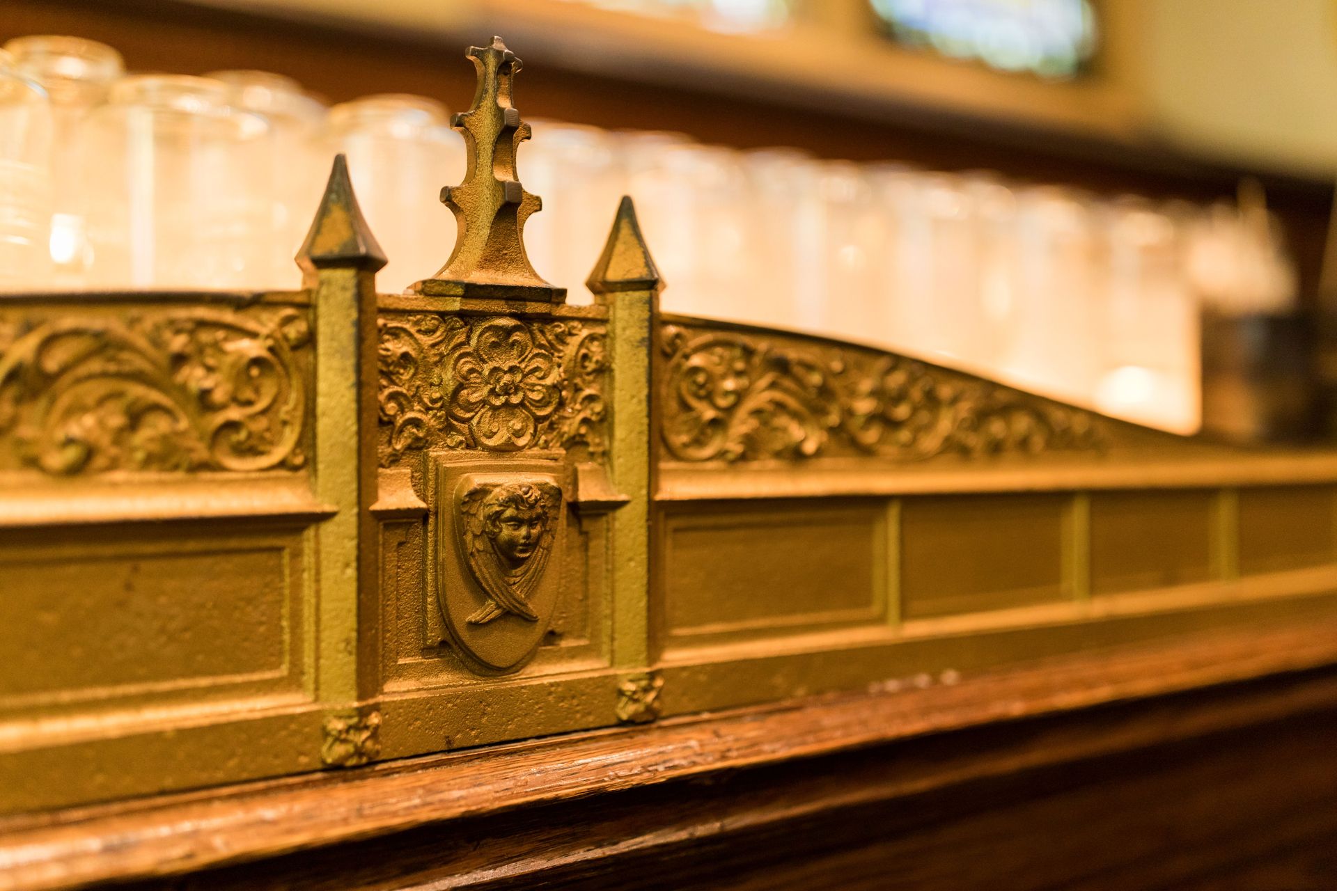 Gold ornamental rail with engraved crest in a warmly lit interior on a wooden counter