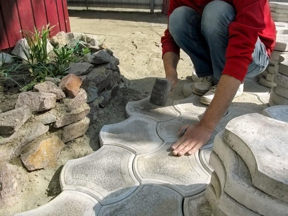 a man in a red sweater is kneeling down on a concrete surface .