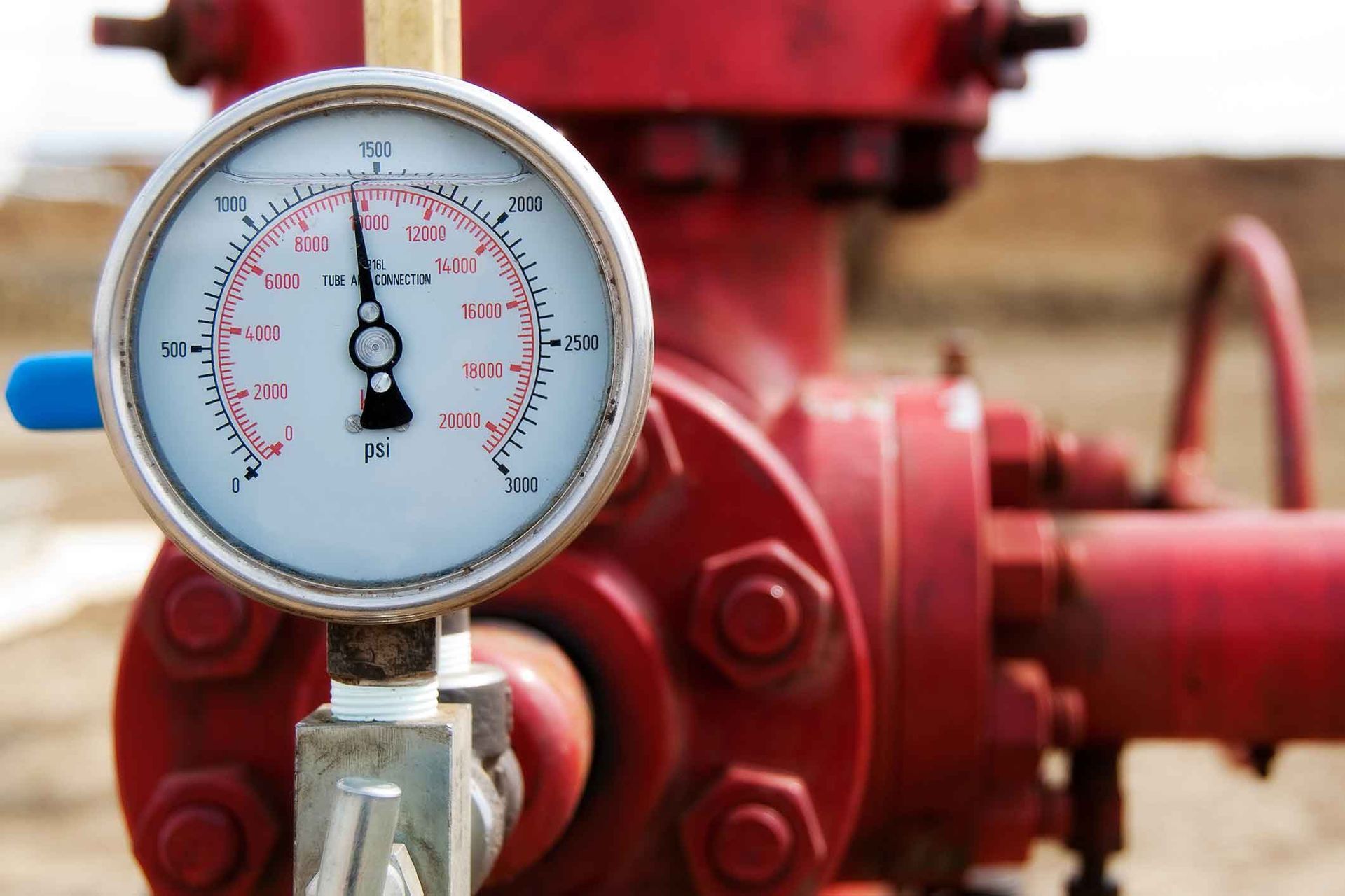 A close up of a pressure gauge on a red pipe
