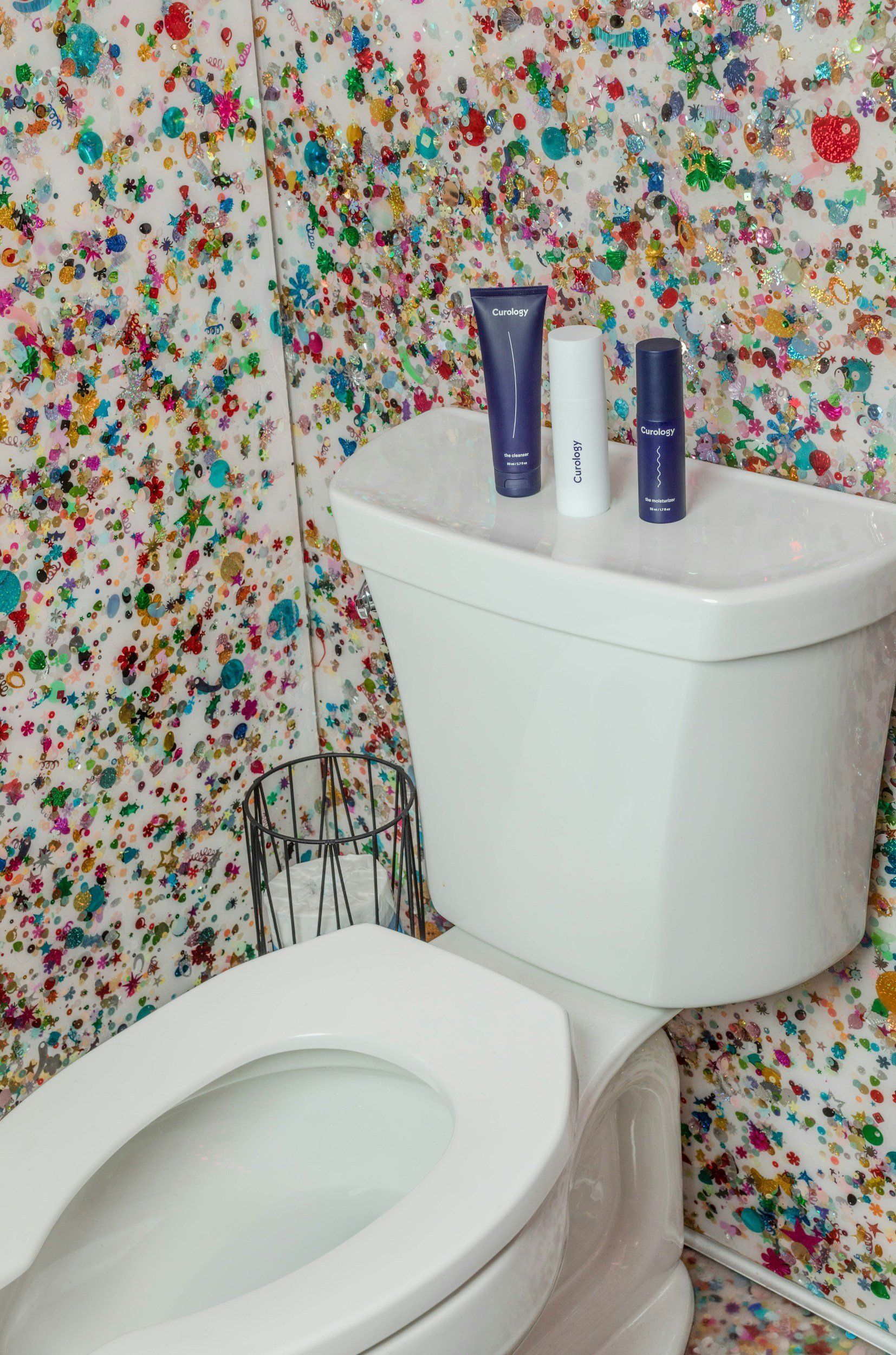 Two bottles of lotion are sitting on top of a toilet in a bathroom.