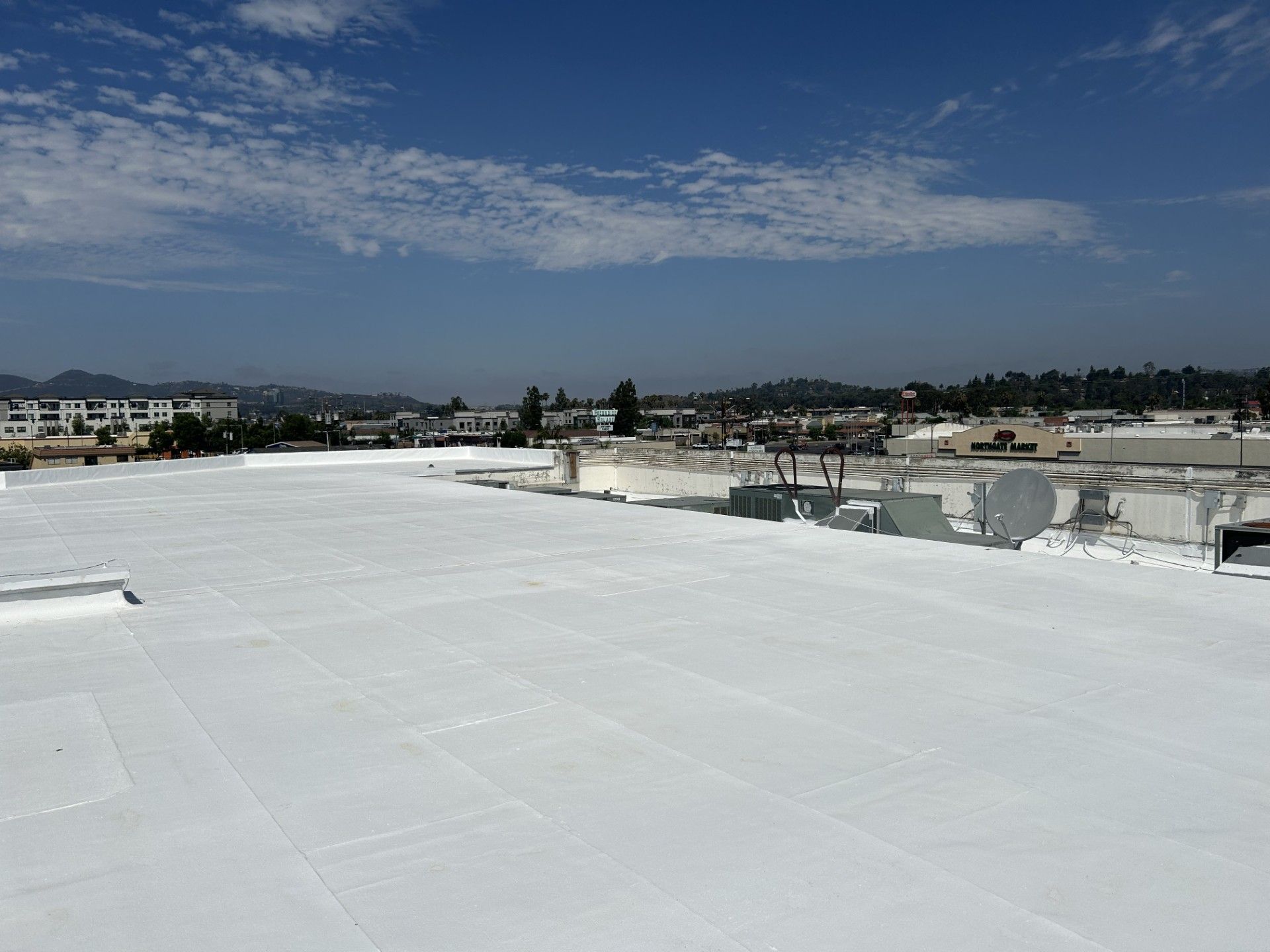 White rooftop with cityscape and cloudy blue sky in the distance
