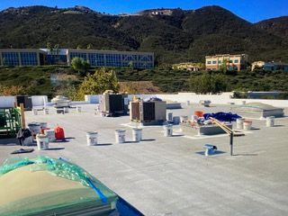 Rooftop with construction materials and workers, mountains in the background.