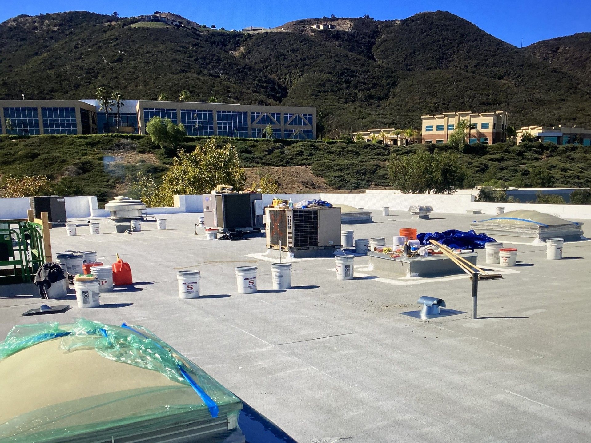 Rooftop construction site with workers, materials, and mountains in the background