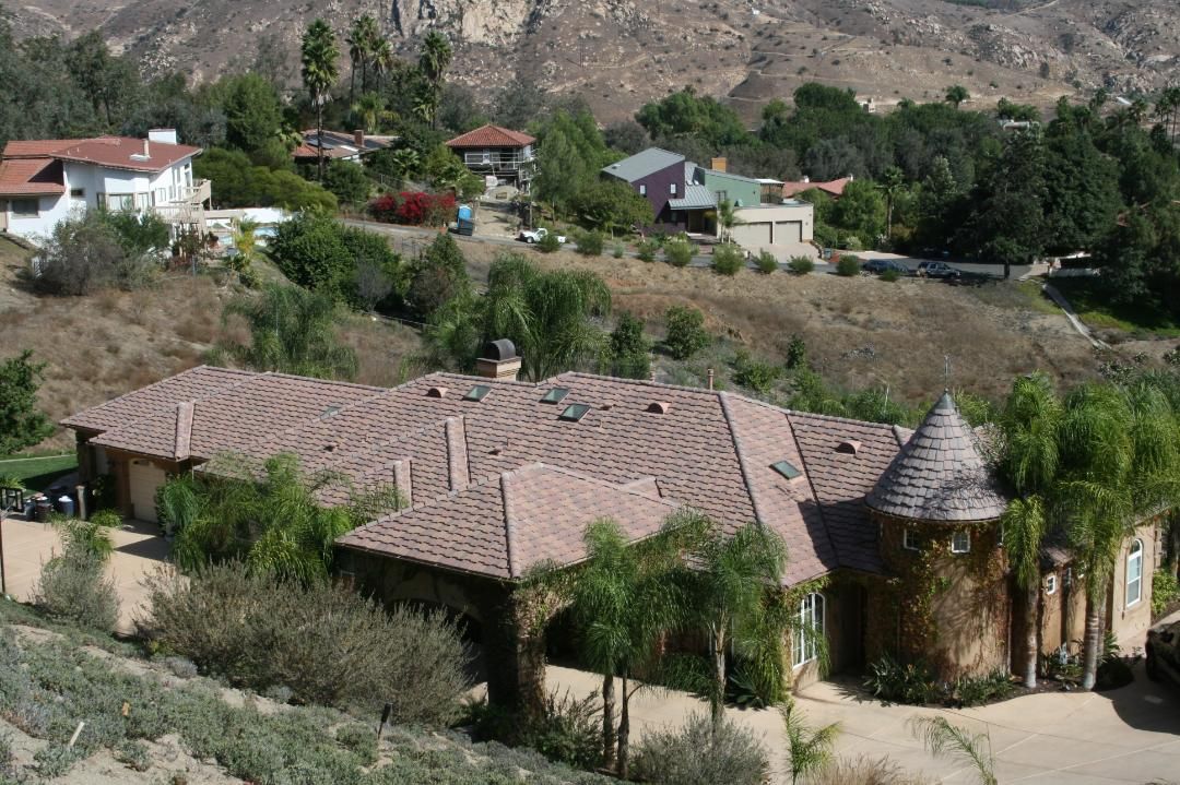 Rural hillside houses with red tile roofs among trees and rocky hills