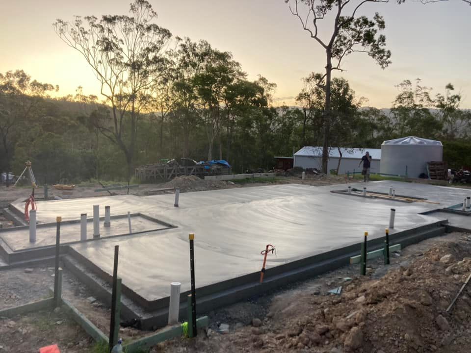 A Concrete Floor is Being Built in a Field With Trees in the Background — Crete to Coast Concreting in Coomera, QLD