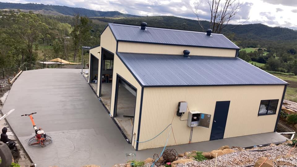 A Large Building With a Blue Roof is Sitting on Top of a Hill — Crete to Coast Concreting in Logan, QLD