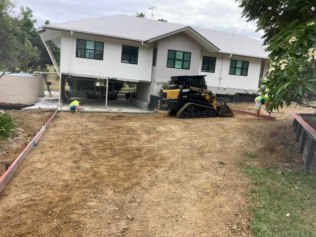 A Bulldozer is Parked in Front of a House Under Construction — Crete to Coast Concreting in Coomera, QLD