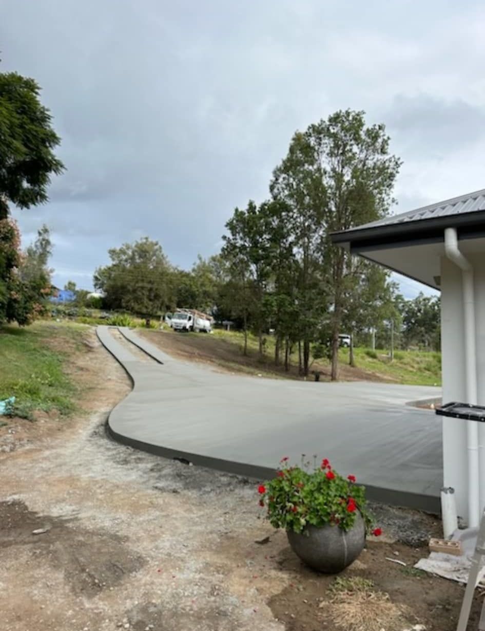 A Concrete Driveway is Being Built Next to a House — Crete to Coast Concreting in Browns Plains, QLD