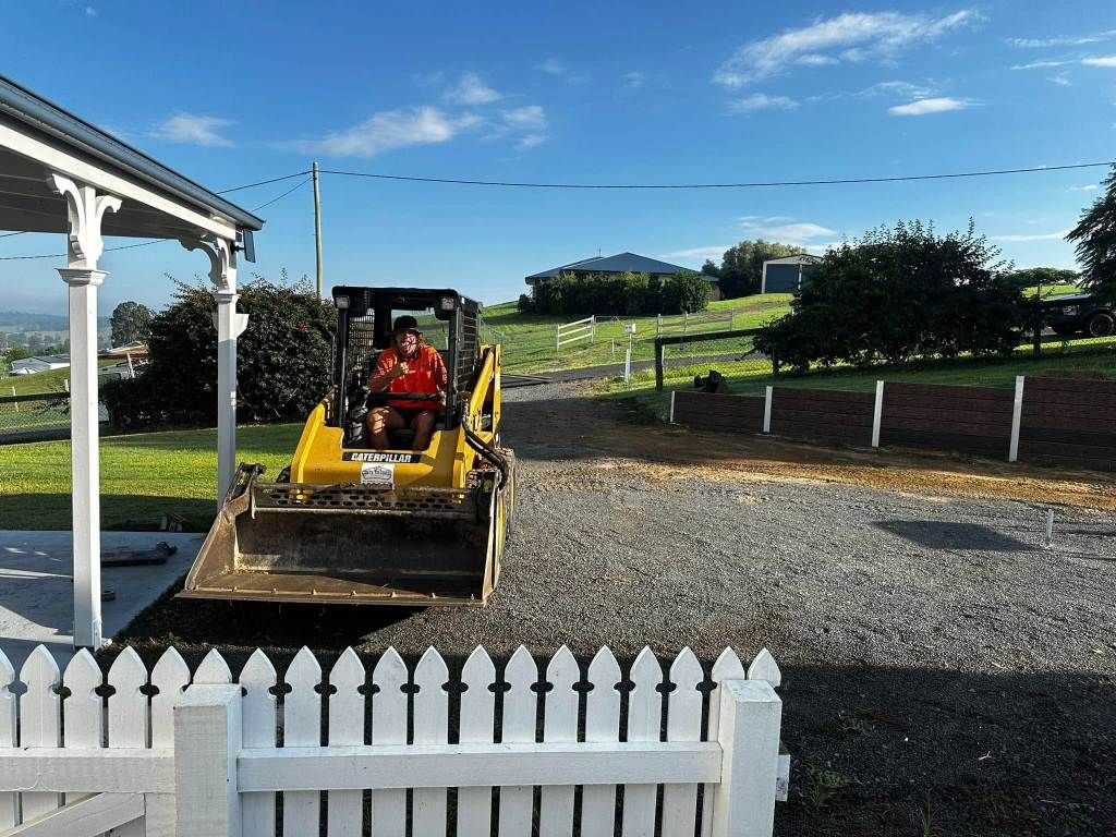 A Man is Driving a Bulldozer on a Gravel Road — Crete to Coast Concreting in Coomera, QLD