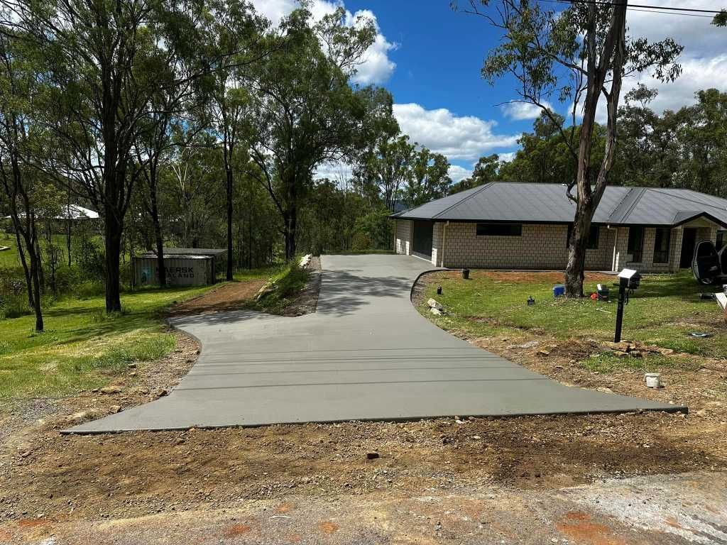 A Concrete Driveway Leading to a House Surrounded by Trees — Crete to Coast Concreting in Browns Plains, QLD