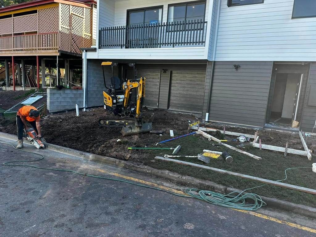 A Construction Worker is Working on a Sidewalk in Front of a House — Crete to Coast Concreting in Tamborine Mountain, QLD