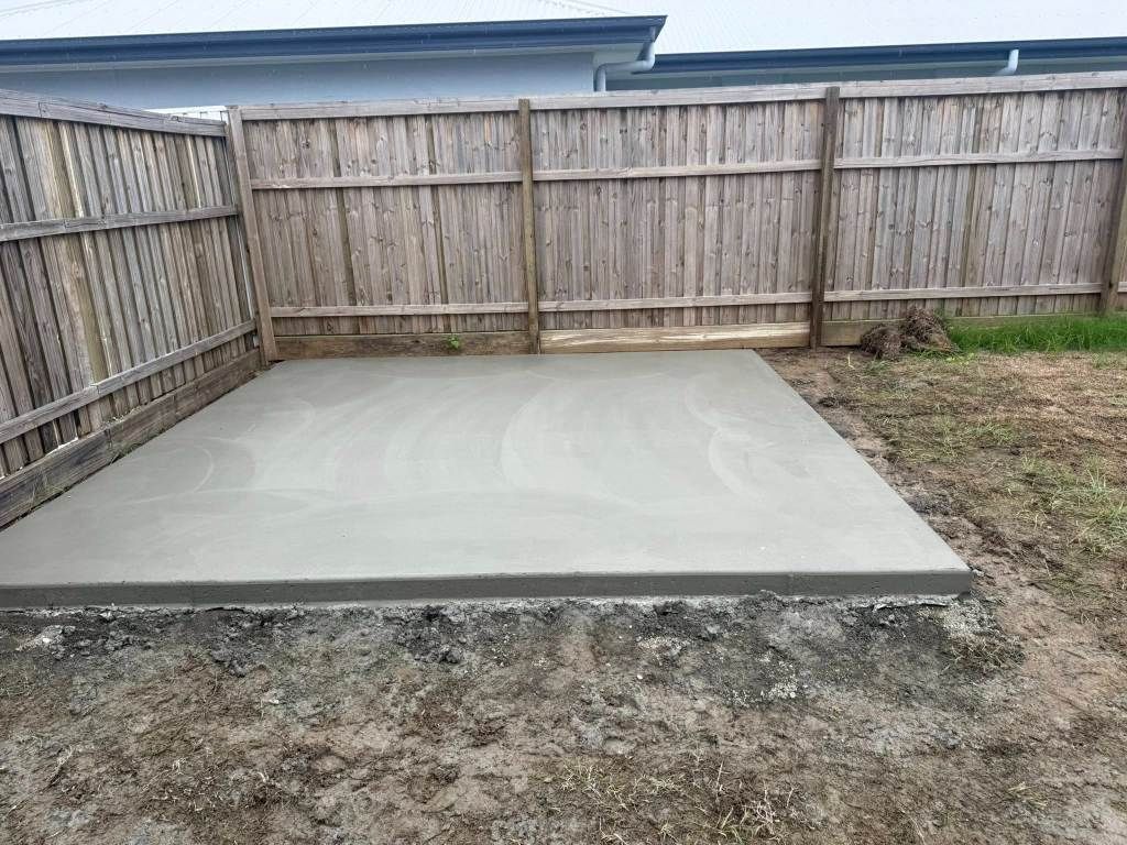A Concrete Slab in a Backyard Next to a Wooden Fence — Crete to Coast Concreting in Canungra, QLD