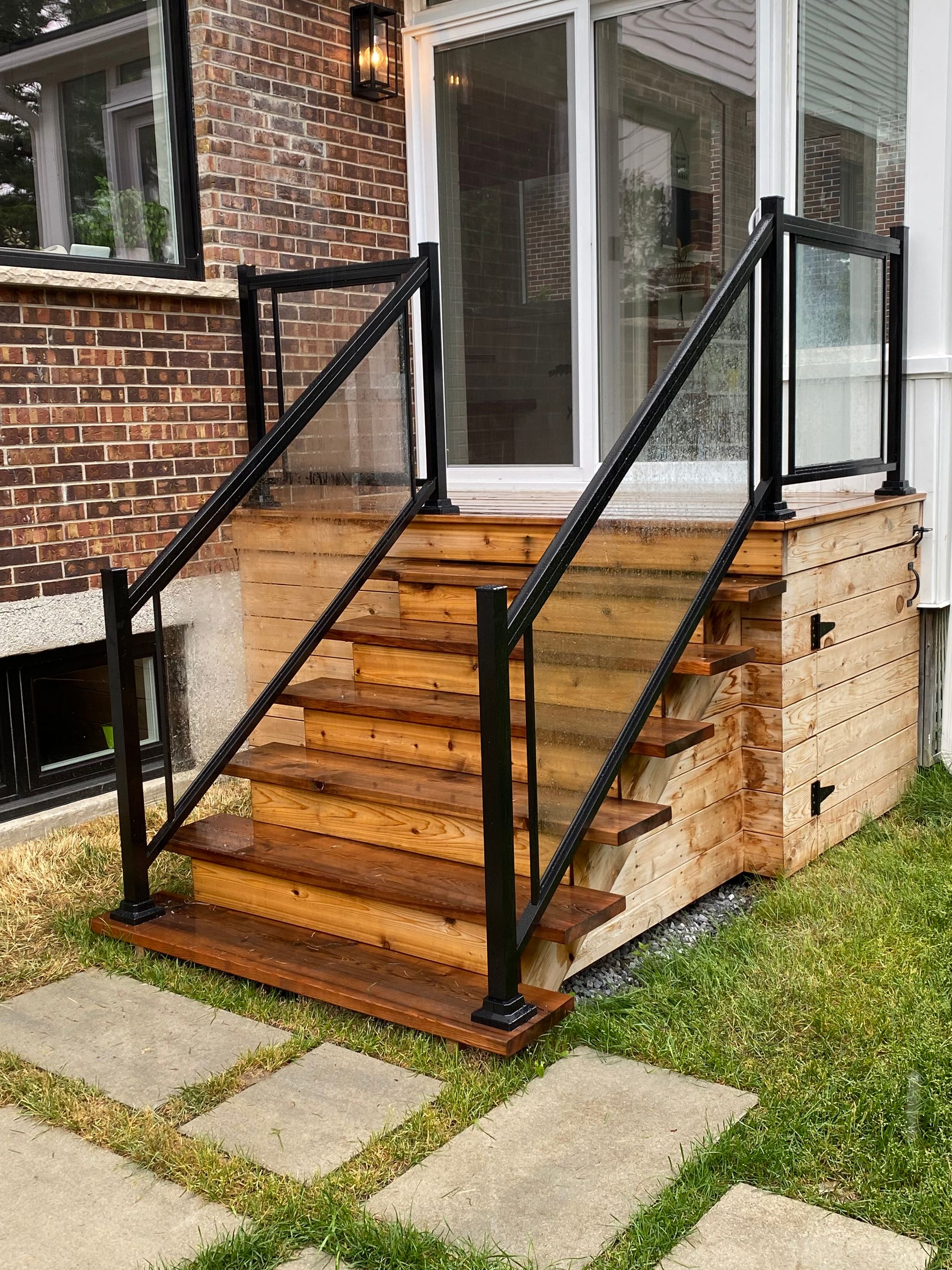Une terrasse en bois avec escalier et garde-corps en verre.