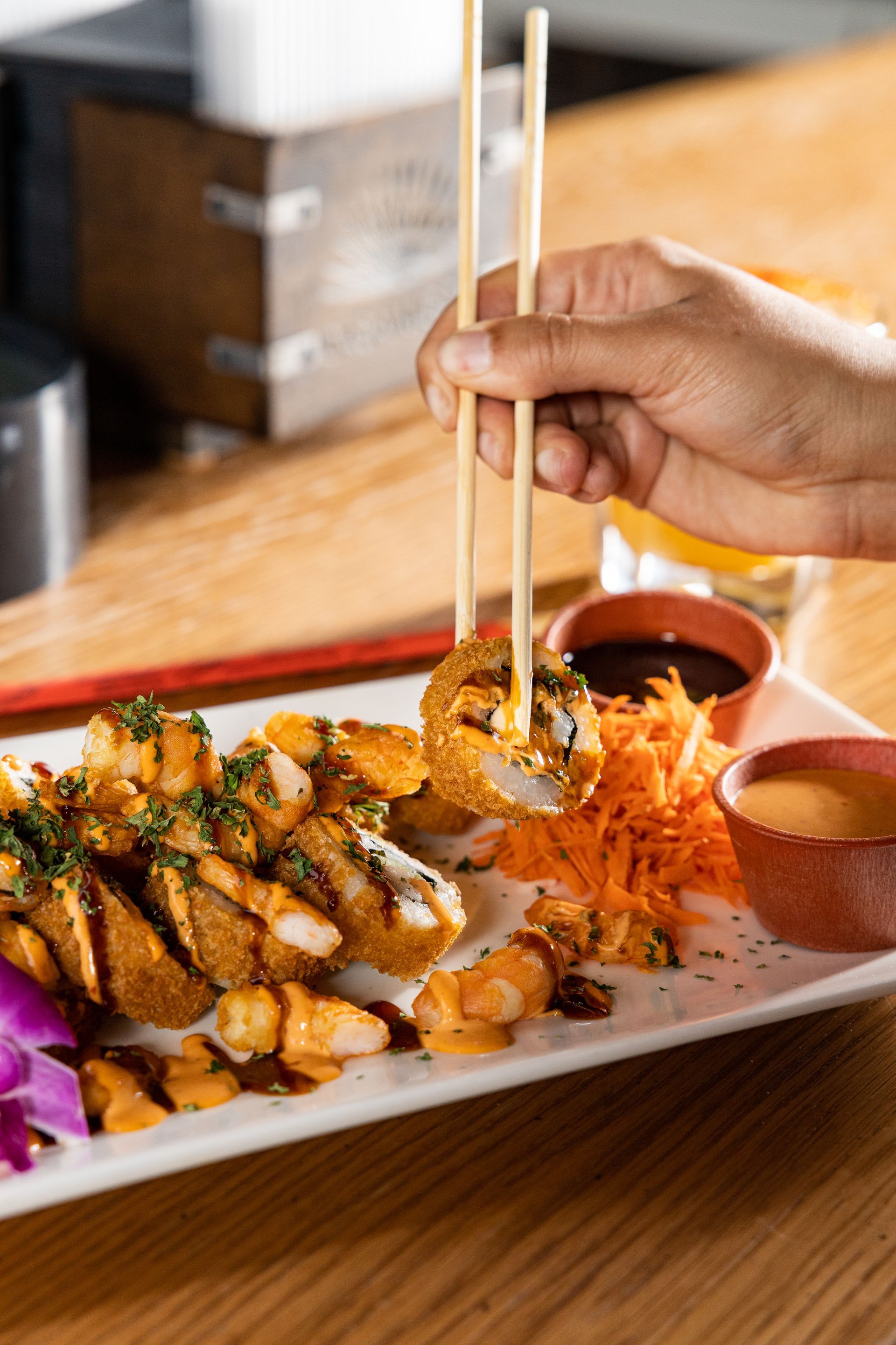 A person is holding chopsticks over a plate of food.