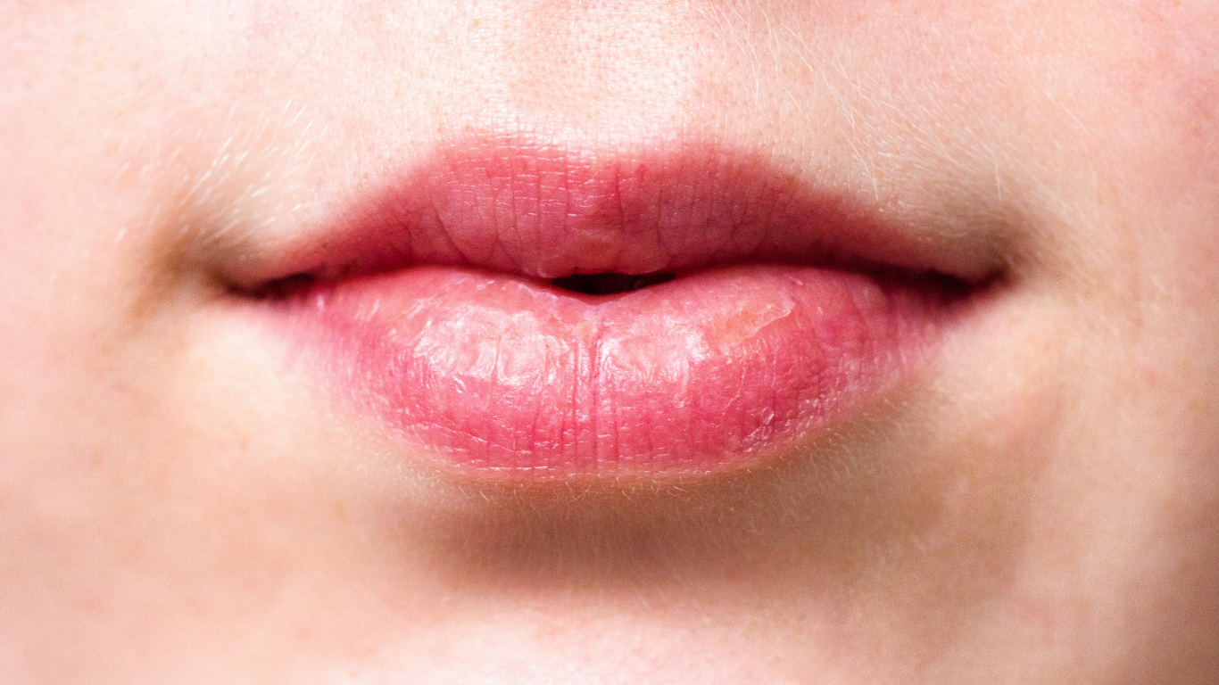 Close-up of closed pink lips and lower face against a light background