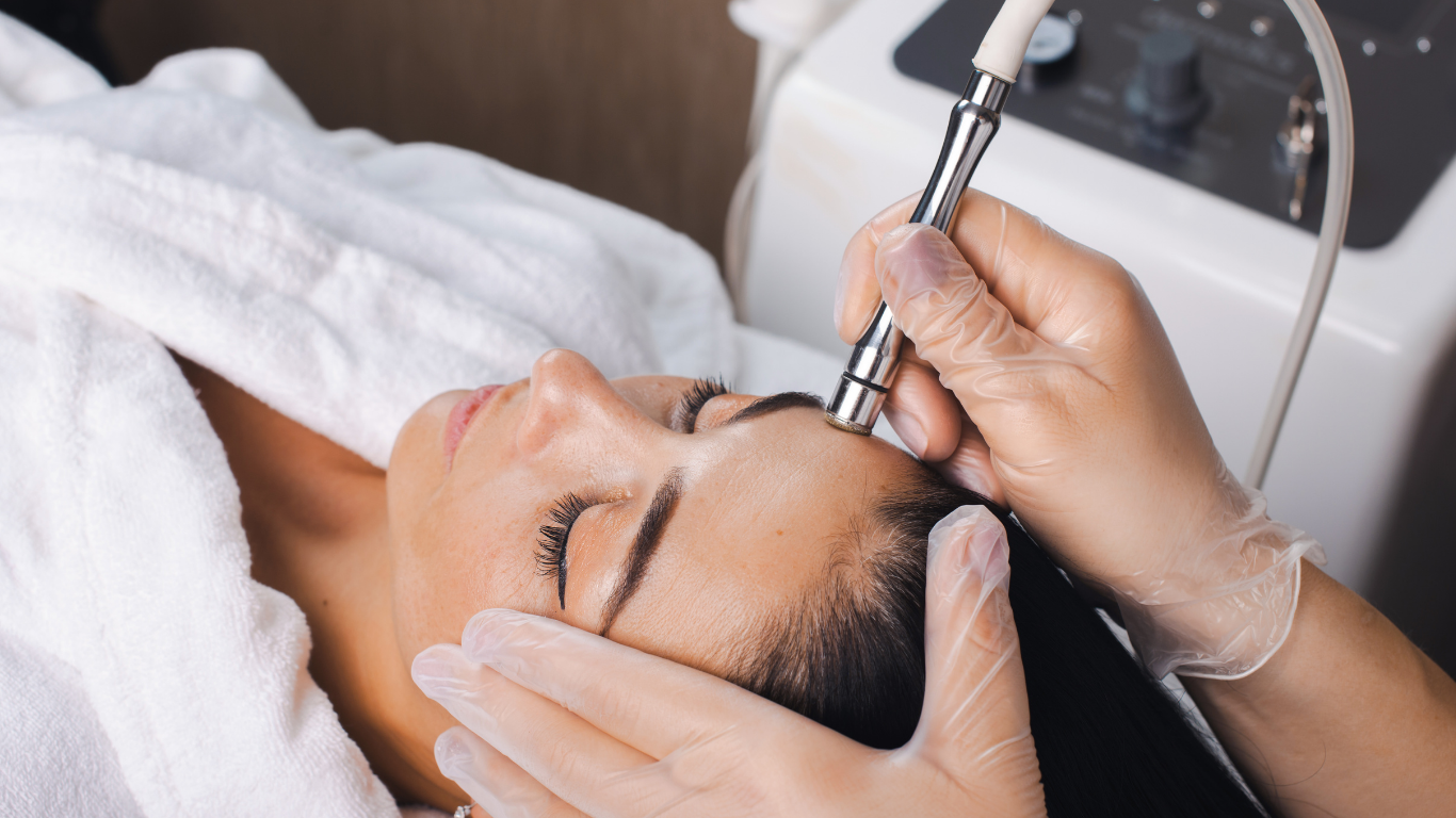 Facial spa treatment with a woman lying down while a gloved esthetician uses a handheld device on her face