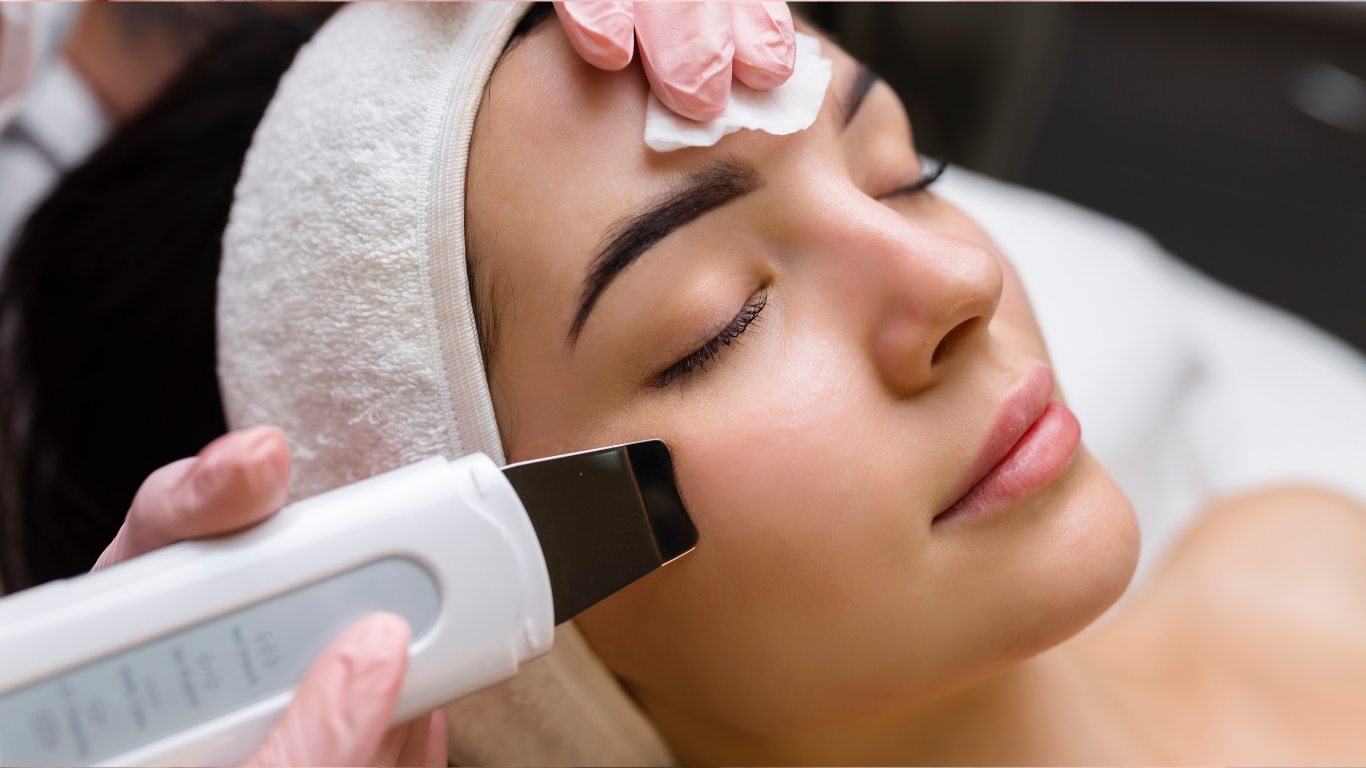 Spa treatment with gloved hands using a facial device on a reclining woman's cheek